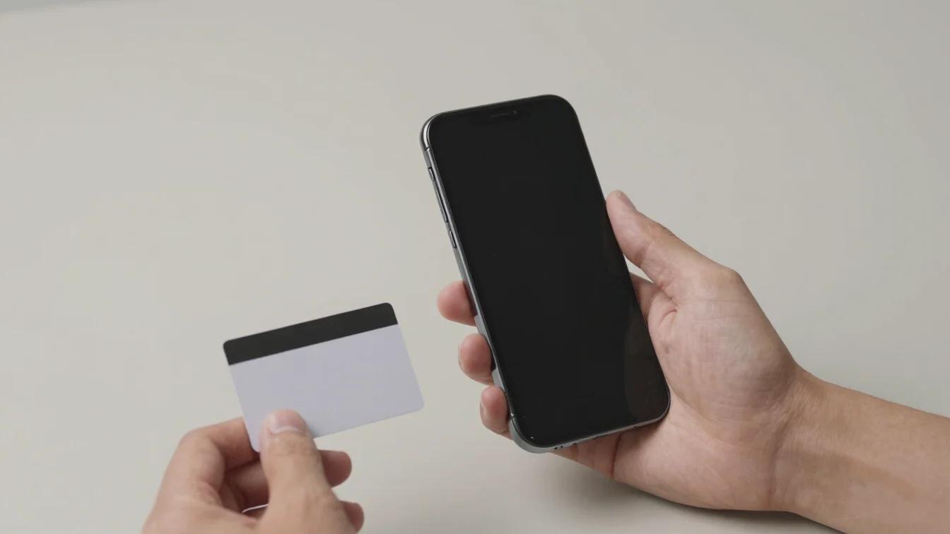 Hands holding a mobile phone beside a simple recharge card on a c